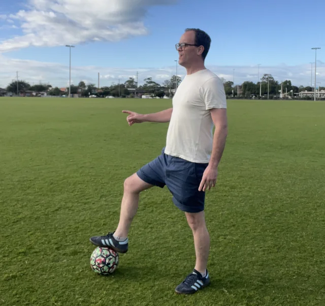Max pointing at a soccer ball on a field