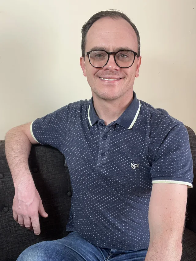 Max relaxing on a sofa and smiling